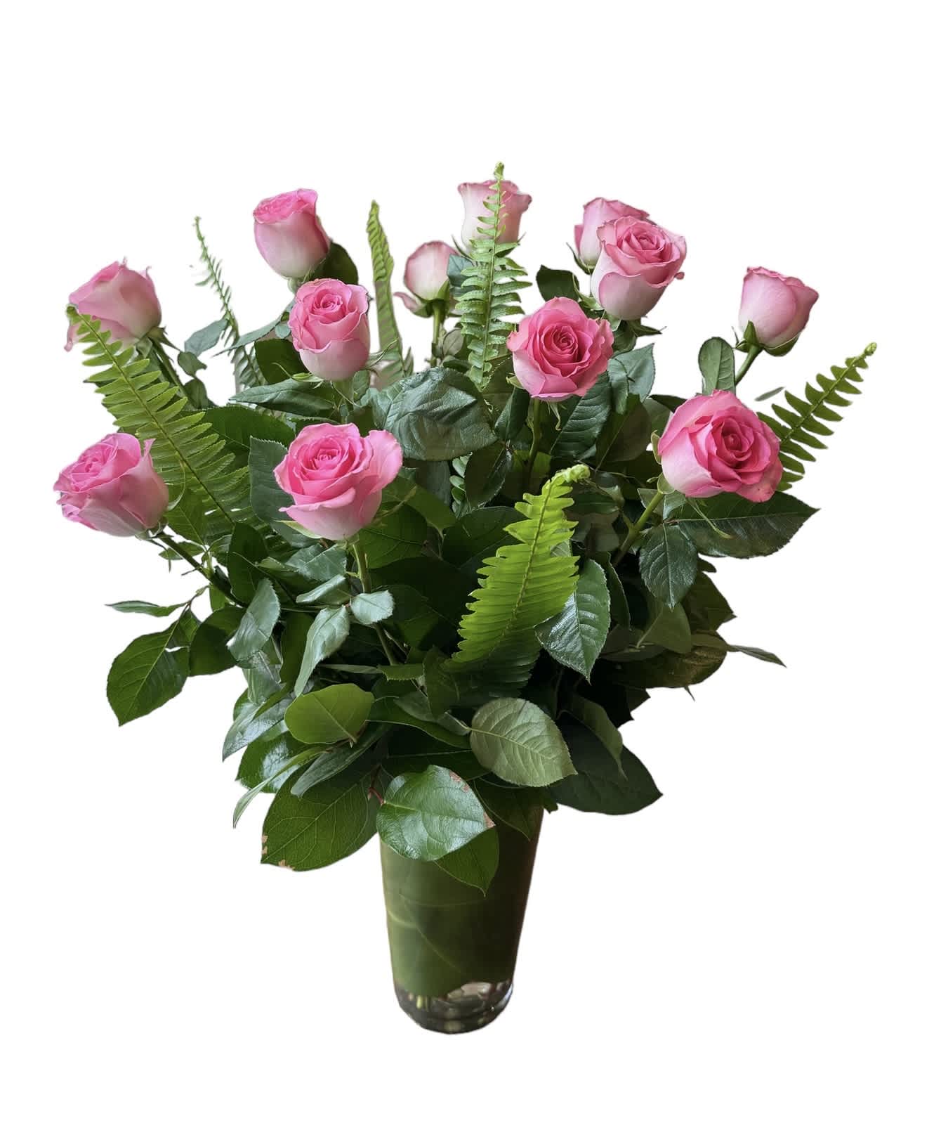 Pink roses arranged in a tall glass vase with fern foliage