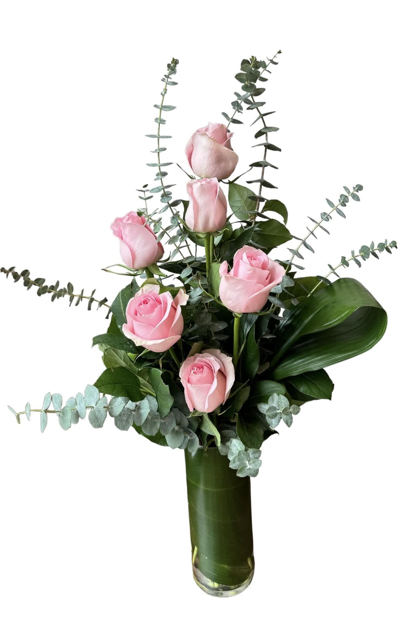 Pink roses arranged in a tall glass vase with eucalyptus foliage