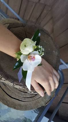 White floral wrist corsage with ribbon on a person's wrist
