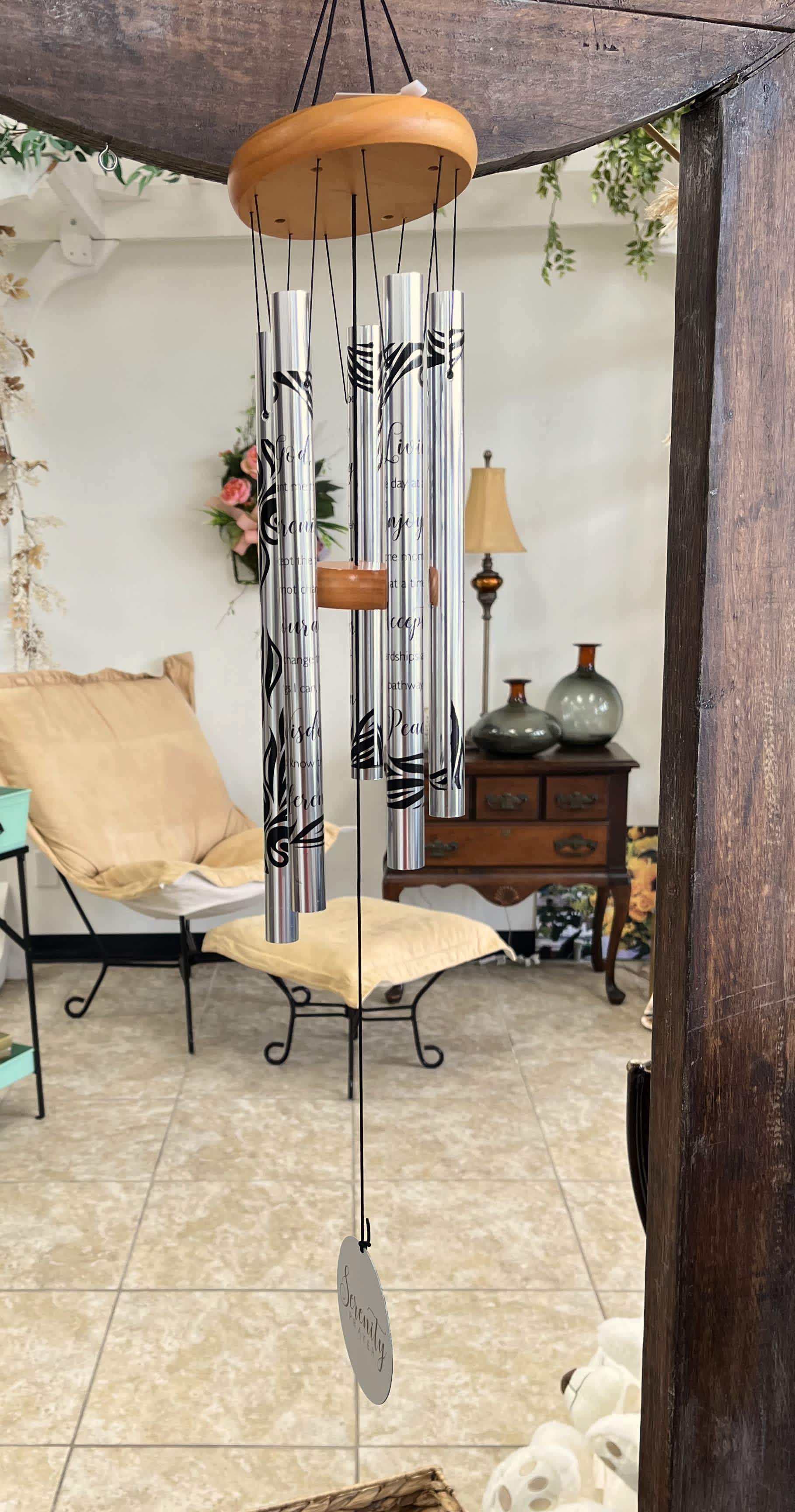 Hanging silver wind chime with black lettering and a round tag