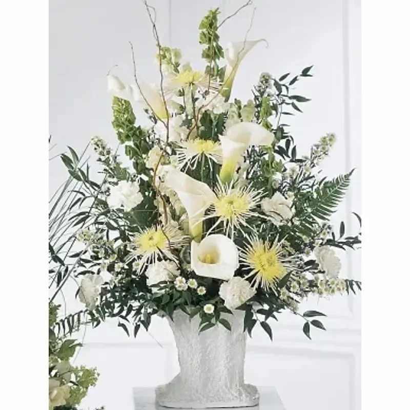 FTD® Solemn Offering Arrangement™ - A traditional sympathy arrangement in white. This elegant arrangement features white calla lilies and white spider chrysanthemums accented with Bells of Ireland, white snapdragons, and white carnations. Appropriate to send to a home or to a funeral. 