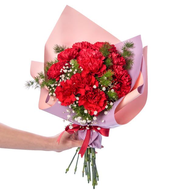Handheld bouquet of red carnations wrapped in pink and lavender paper