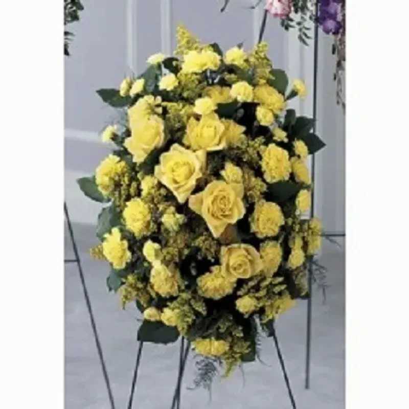 Sunshine Of Rays - Sunshine Of Rays greets a memorial service with dignified brightness-the tall standing spray built for sympathy or funeral occasions. The arrangement's oval silhouette of yellow roses and clustered yellow carnations reads as both respectful and uplifting, the kind of floral tribute that helps the person you're honoring feel remembered and celebrated at a service.  Dense layers of yellow roses, yellow carnations and chrysanthemums are set against deep green foliage for strong contrast and a formal, full appearance. Designed for standing display, the spray is mounted on a sturdy metal floral easel so it presents at the proper height beside a casket or memorial table. The color palette of warm yellow, crisp white highlights and rich green leaves creates a calm, hopeful presence without being showy.  For families arranging a service, Sunshine Of Rays offers a traditional, tasteful option that communicates sympathy and warm remembrance. Order with the easel included for immediate standing display; minimal care is needed beyond keeping the spray cool and shaded prior to placement at the service.