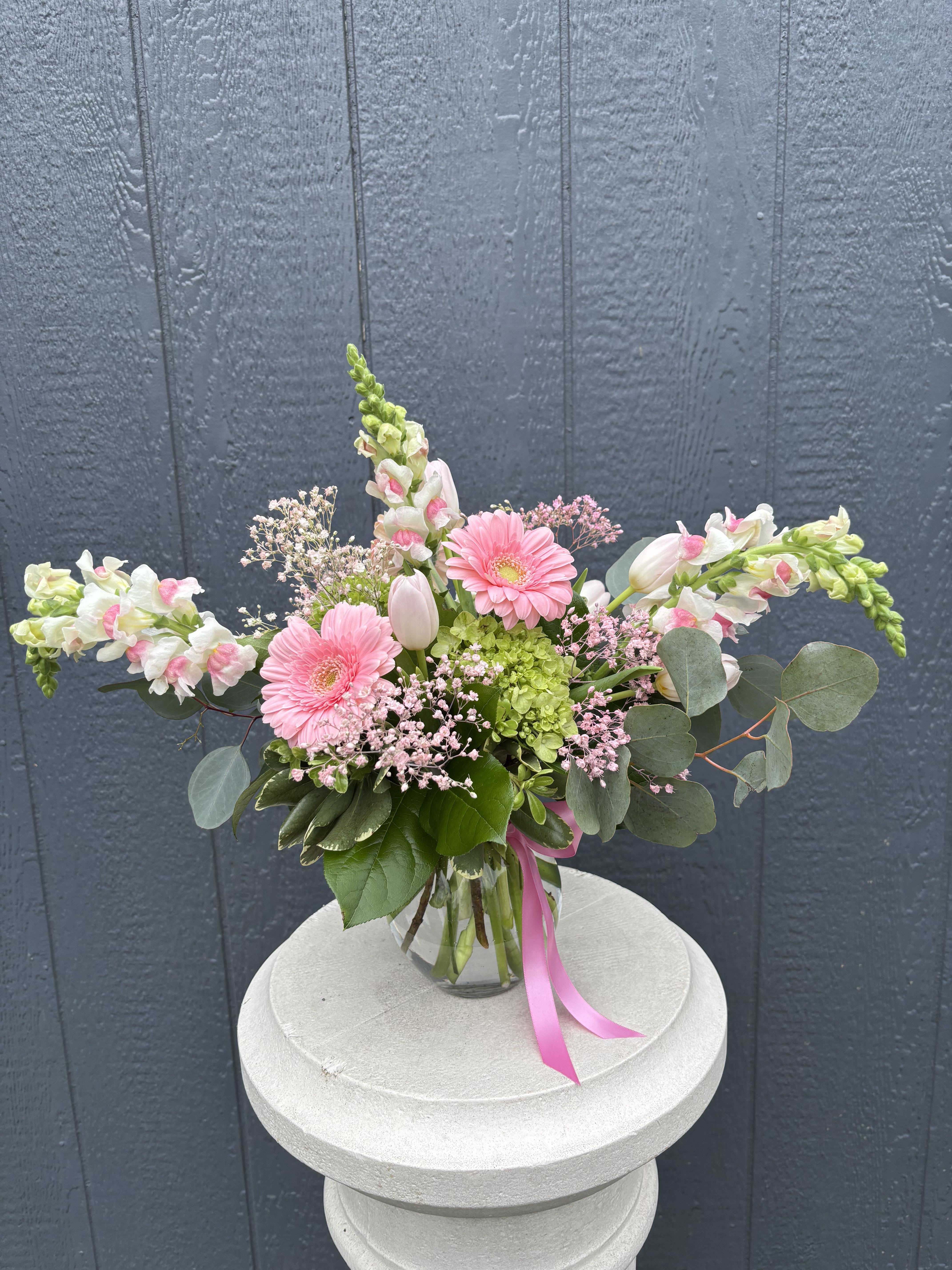 JUST BECAUSE PINK - “Just for Mom” feels like a love letter in blooms—soft, joyful, and full of heart. This arrangement features delicate pink gerbera daisies, tulips, and snapdragons, nestled among airy filler flowers and fresh greenery. Accented with a sweet ribbon and designed in a clear glass vase, it’s the perfect way to say “thank you,” “I love you,” and everything in between.