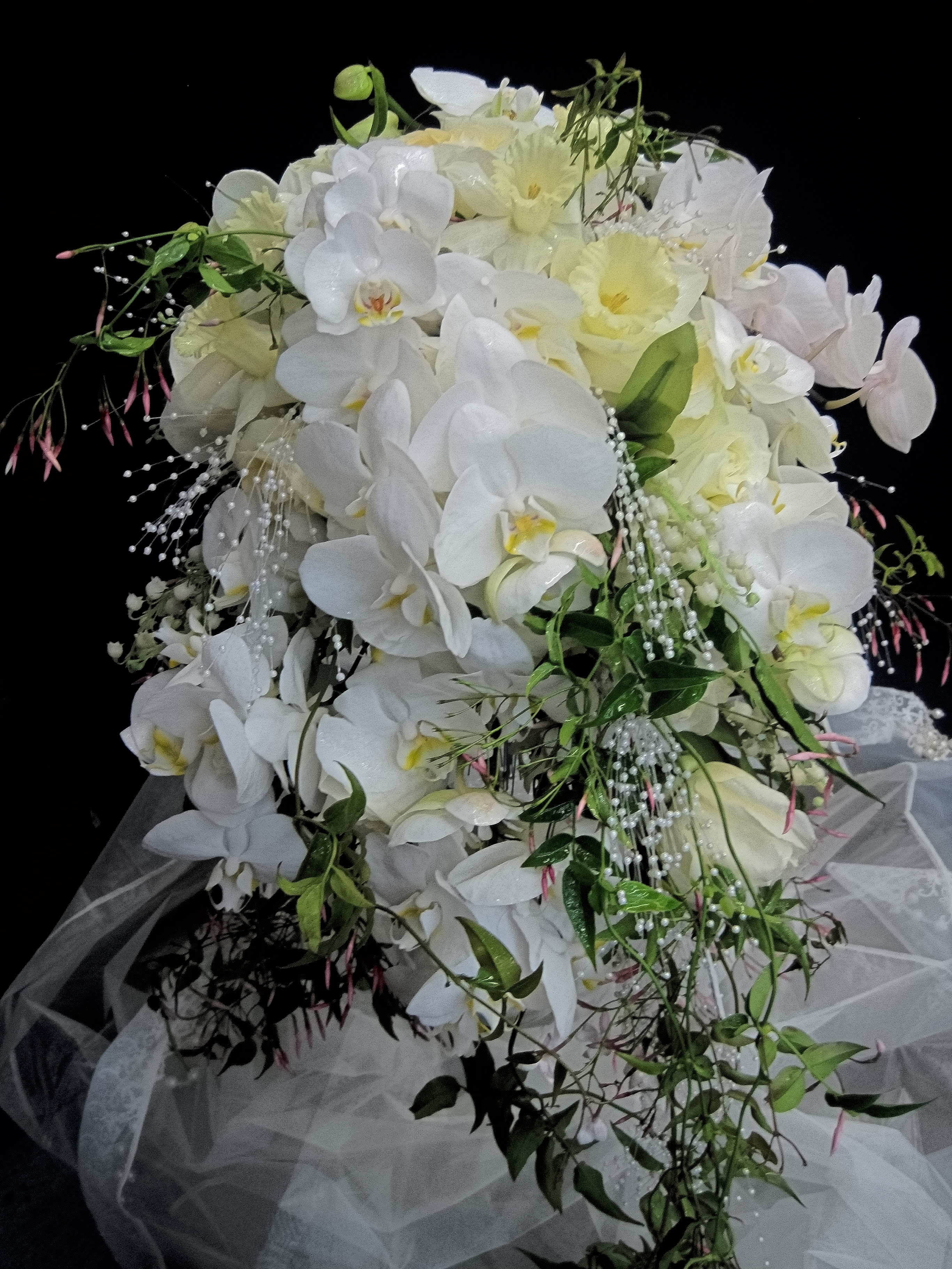 White orchid bouquet with pale yellow flowers and trailing greenery