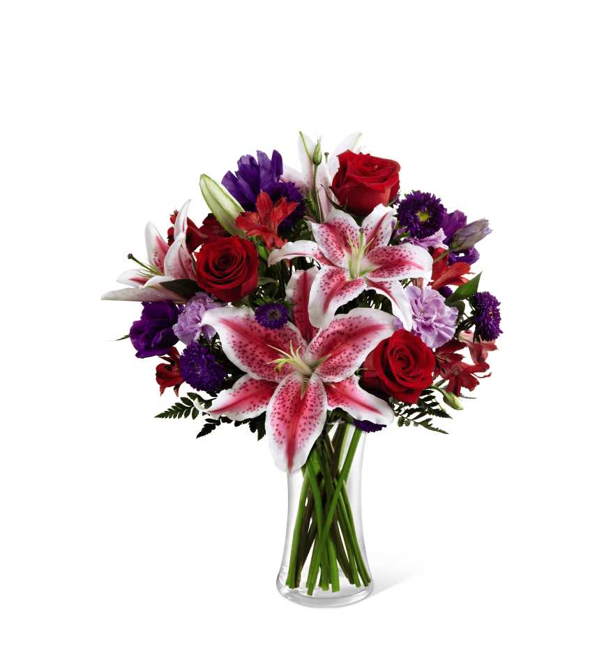 Bouquet of red roses and pink lilies in a clear glass vase