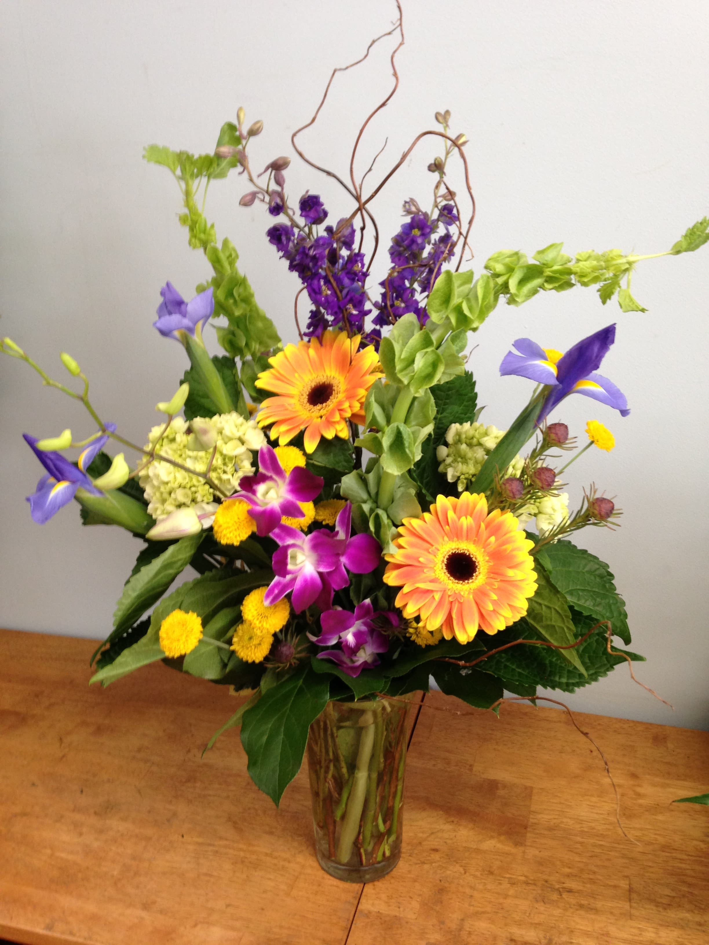 Colorful mixed bouquet in a clear glass vase with orange gerberas and purple blooms