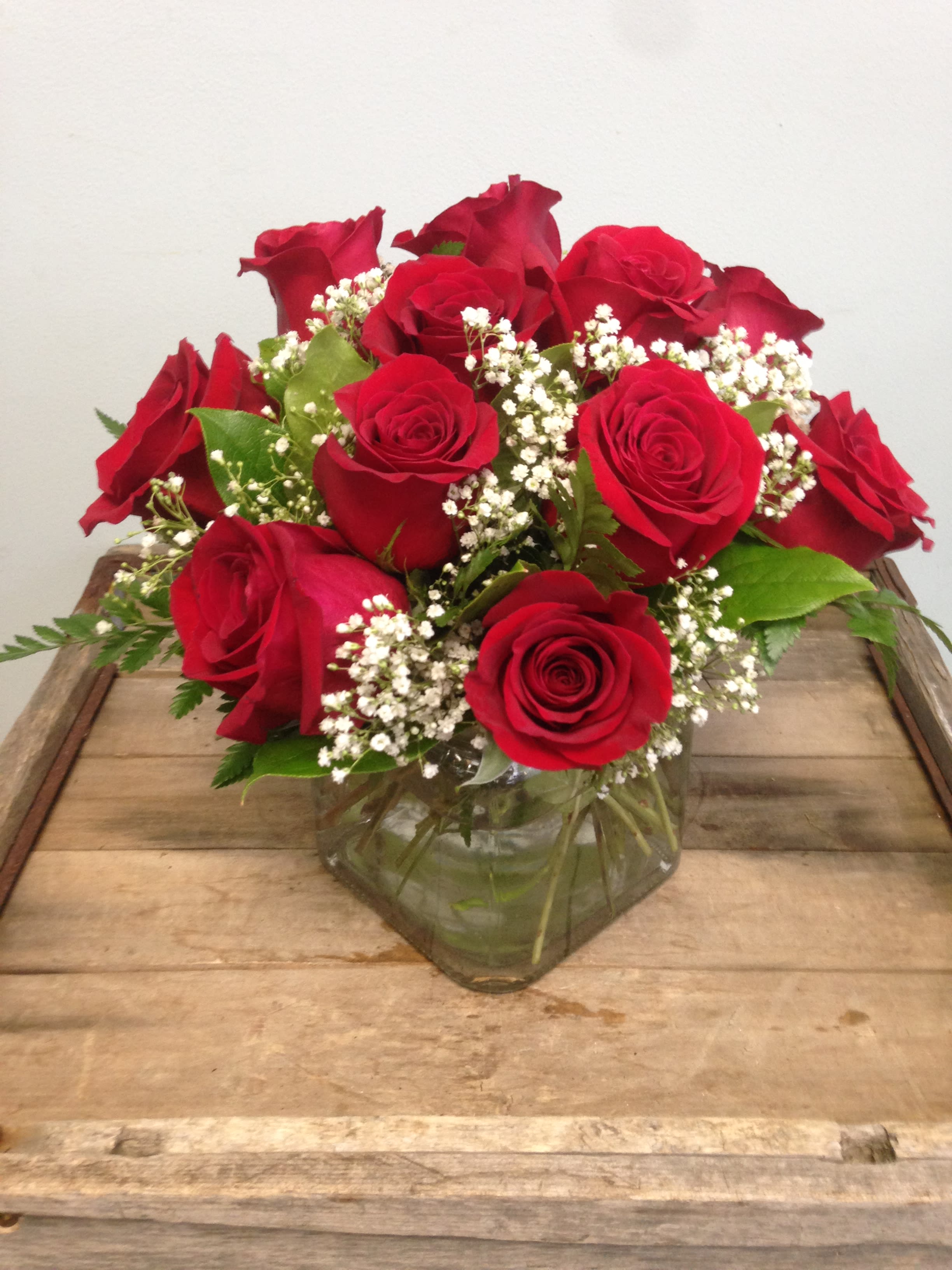 Red roses arranged in a clear glass vase with white filler flowers