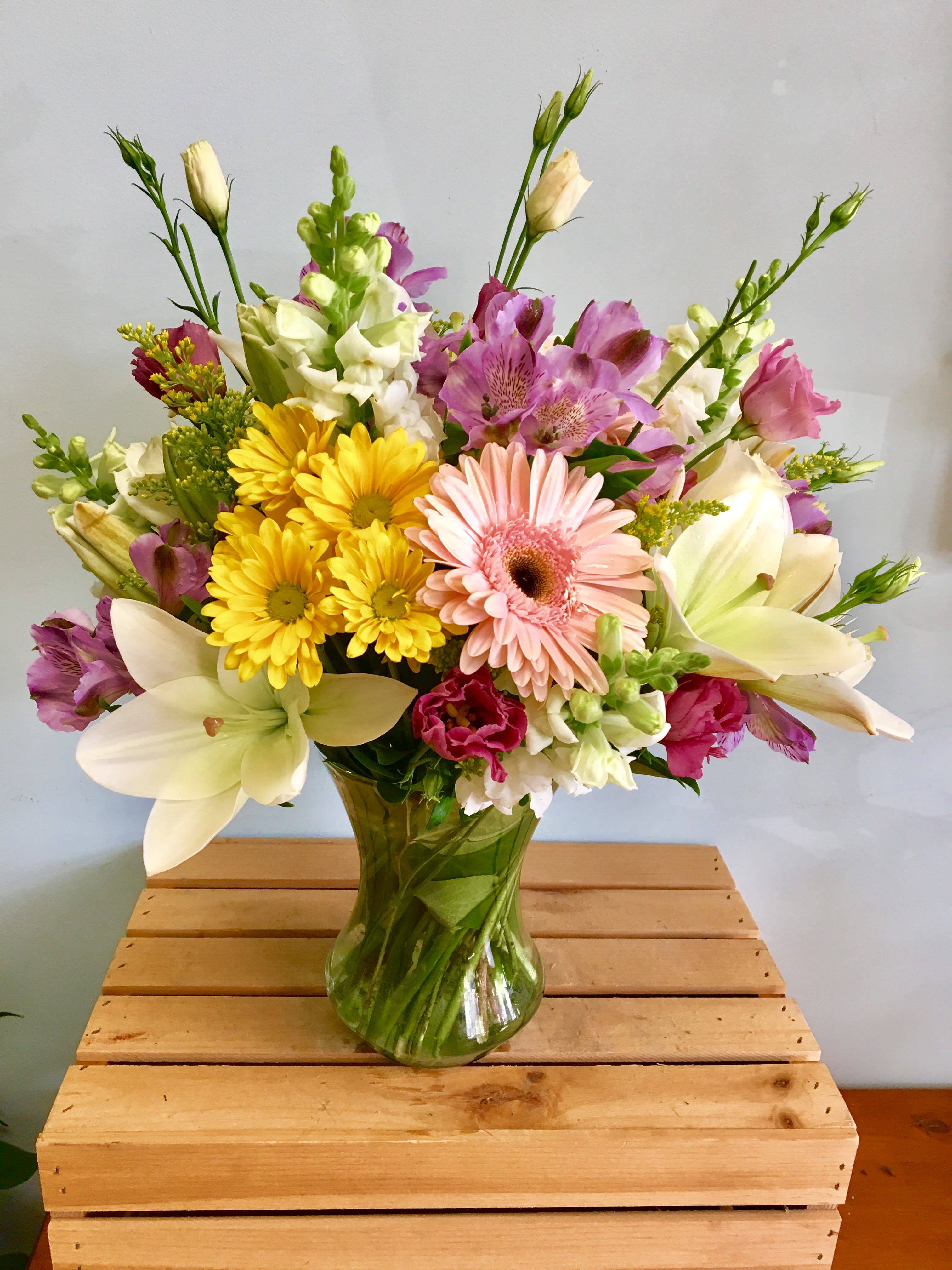 Mixed bouquet of pink, yellow, and white flowers in a glass vase