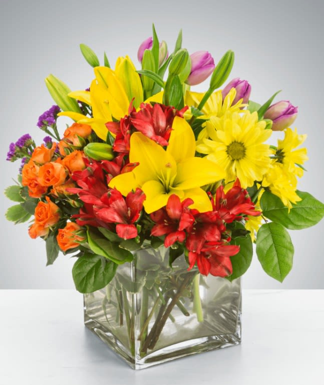 Bright mixed bouquet in a clear square glass vase