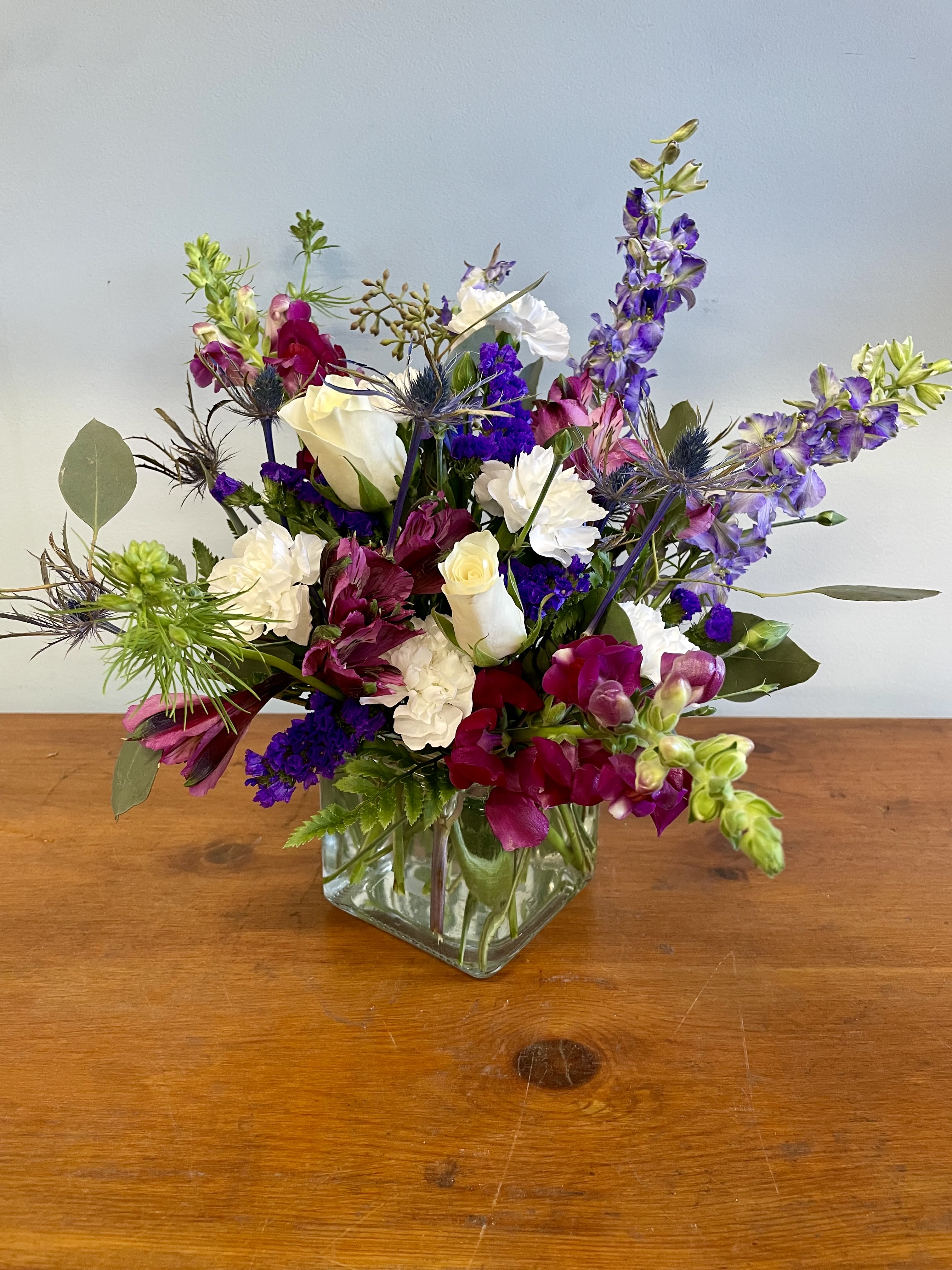 Mixed bouquet in a square glass vase with white, purple, and pink flowers