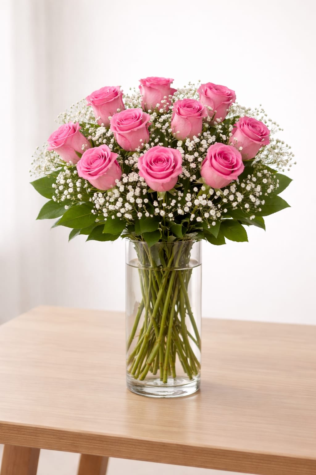 Pink roses arranged in a clear glass vase with white filler flowers
