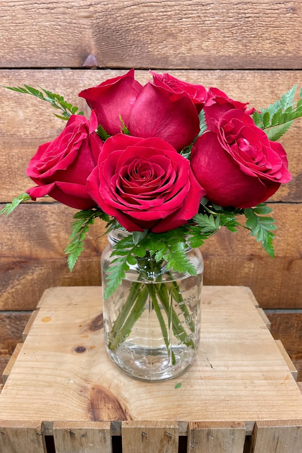 Red roses arranged in a clear glass jar vase