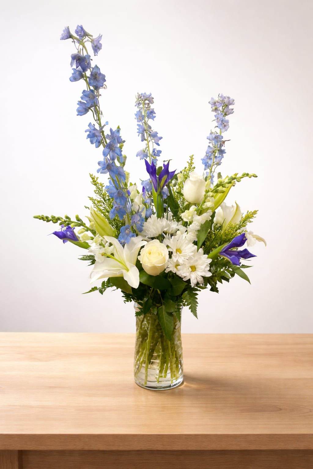 Tall mixed bouquet in a glass vase with blue, white, and purple flowers