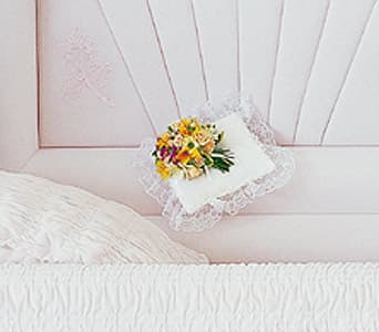 Small floral pillow with lace trim on a pink bedspread