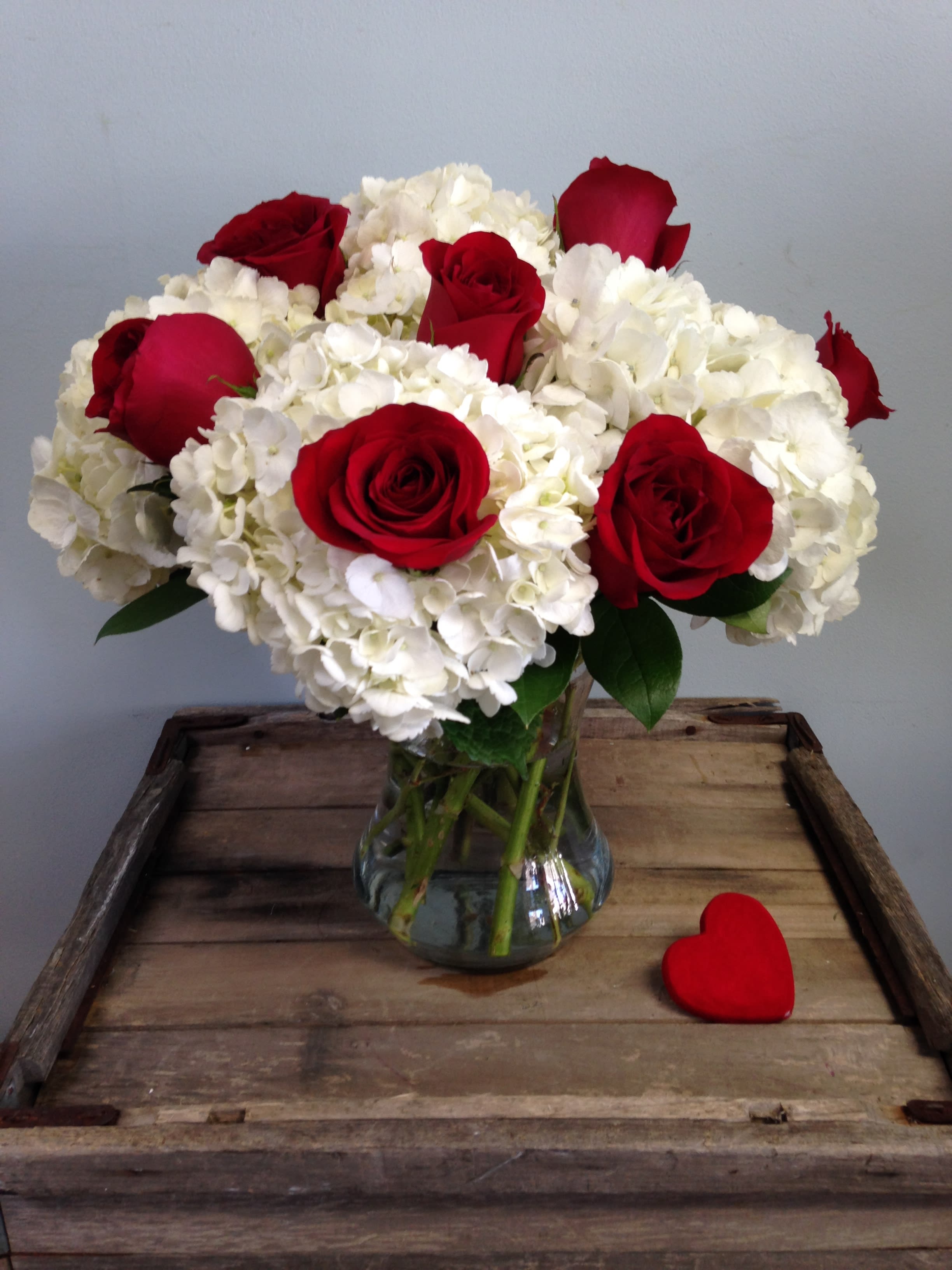 Red roses and white hydrangeas arranged in a glass vase