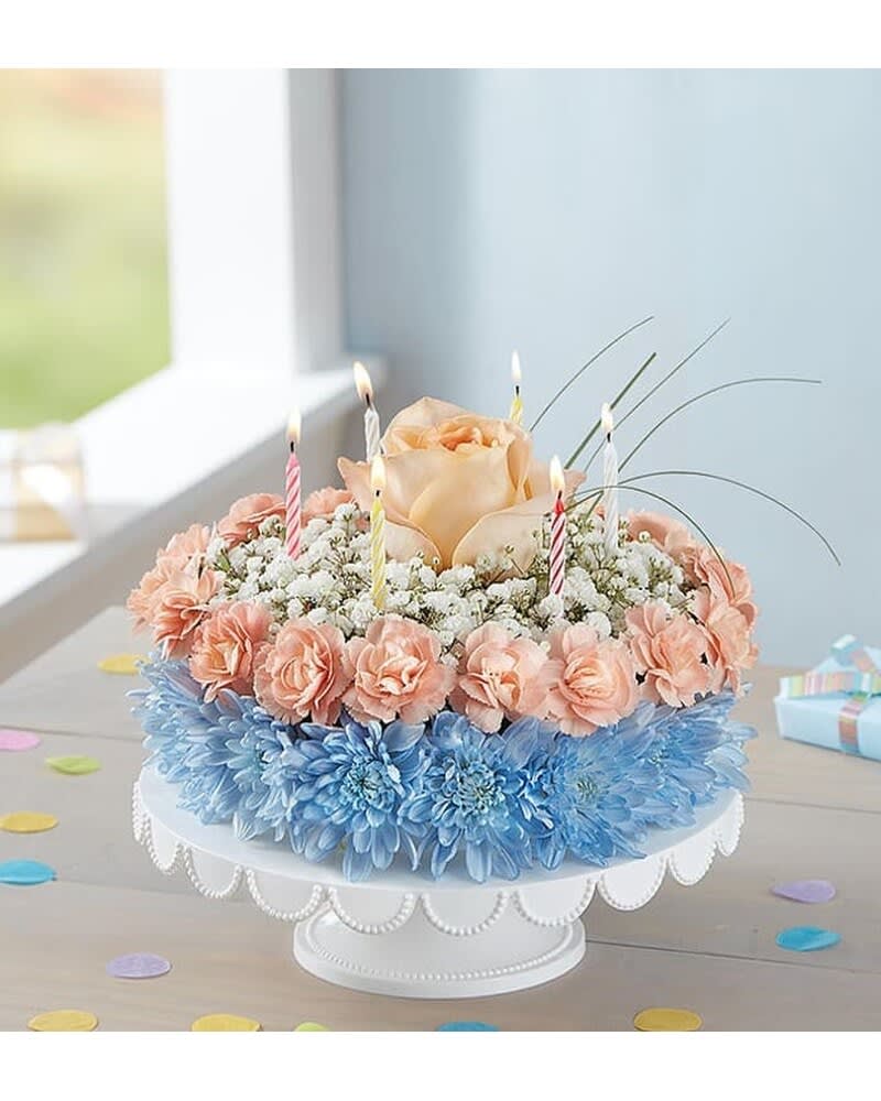 BIRTHDAY WISHES FLOWER CAKE COASTAL - Here’s a birthday favorite that really takes the cake! Our one-of-a-kind flower creation is handcrafted from cool, coastal-colored blooms for a fun, summery gift they won’t soon forget. Take their celebration to new heights of happy by adding a festive balloon.  ****VASE PLATE WILL VARY ******