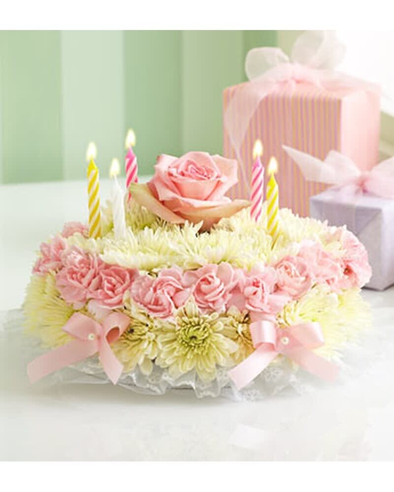 CLASSIC BIRTHDAY WISHES FLOWER CAKE  - Our signature floral birthday cake may look good enough to eat, but it's actually crafted from fresh pastel flowers such as mini carnations or roses and poms. It arrives in a bakery box with a set of candles, and with proper care, can last days after the celebration is complete. Small arrangement measures approximately 4"H x 8"D. Large arrangement measures approximately 7"H x 8"D. This arrangement is hand-designed so colors, varieties, and container may vary. 