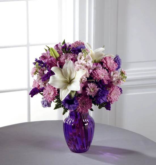 Shades of Purple Bouquet - Everyone loves a little purple in their life - it's elegance, it's twilight magic, it's expression of the unexpected. Send your recipient every shade of purple nature can supply with this flower arrangement, bringing together lavender gilly flower, purple double lisianthus, lavender chrysanthemums, purple Peruvian Lilies, and purple statice, accented with white Asiatic Lilies and lush greens presented in a modern purple swirled glass vase. A wonderful birthday, anniversary, or thank you gift!  ***PURPLE VASE DESIGN WILL VARY***