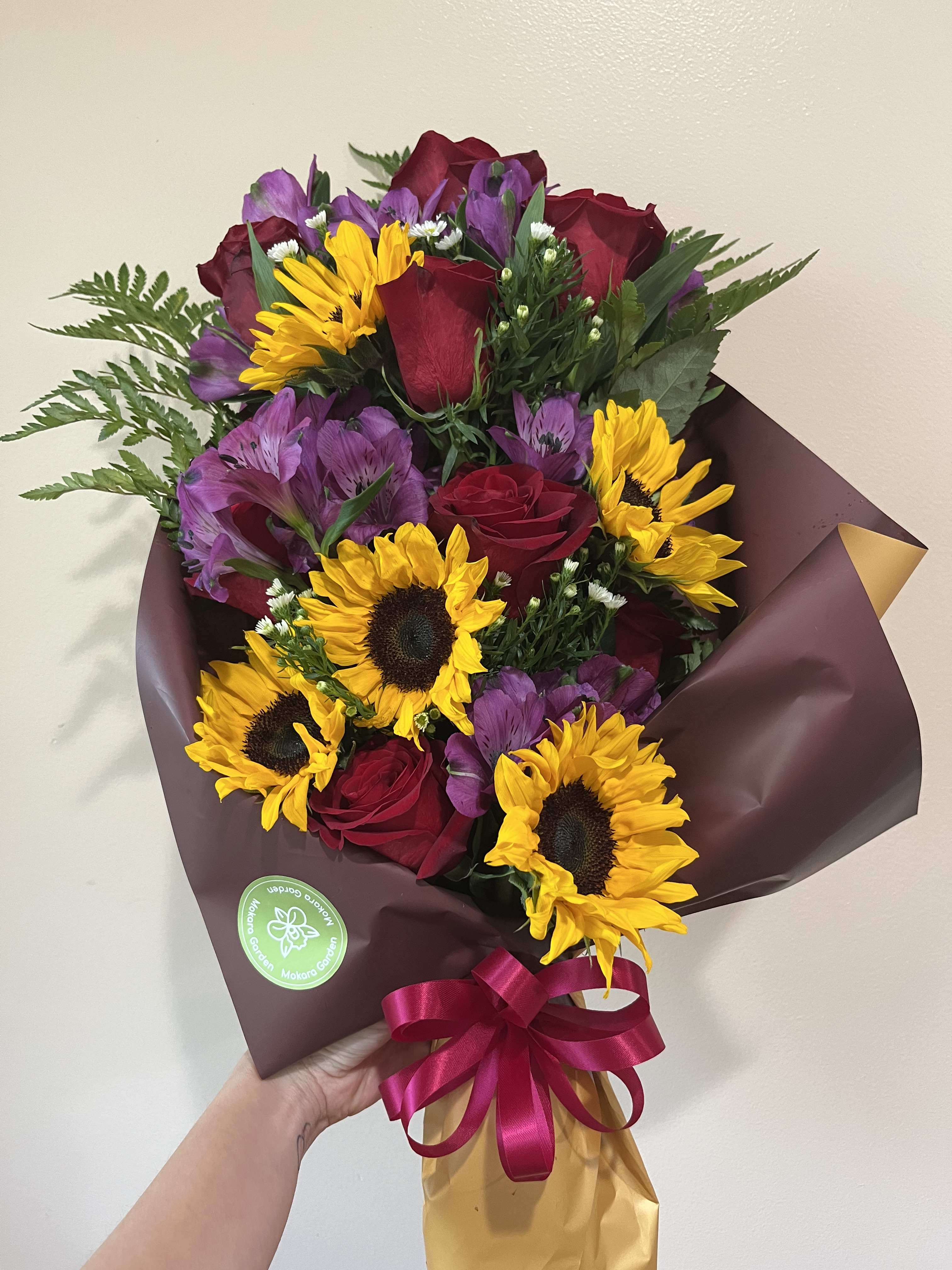 Wrapped Bouquet of 5 Sunflowers and Red Roses  - Wrapped Bouquet of Sunflowers, Purple Alstroemerias, and Red Roses with White Montecasino accents. Paper color may vary depending on availability. 