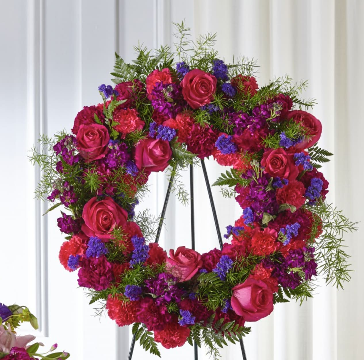 Calming Colors Wreath - The use of color in a sympathy tribute can evoke emotions that words otherwise can’t. In our Calming Colors Wreath, a gorgeous display of bold pinks and comforting purples come together in a timeless expression of sympathy. This arrangement comes expertly crafted by our local florists with stock, roses and carnations to show how much you care.