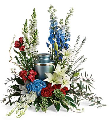 Reflections Of Honor Cremation Tribute - An honorable life deserves an honorable celebration. Beautifully patriotic, this arrangement of blue hydrangea, white orchids and red roses surrounds the cremation urn with proud spirit. This patriotic tribute includes blue hydrangea, white dendrobium orchids, red roses, white asiatic lilies, red alstroemeria, red carnations, blue delphinium, white snapdragons, dusty miller, myrtle, huckleberry, variegated ivy, curly willow, aralia leaves, parvifolia eucalyptus, spiral eucalyptus, and lemon leaf. Arrangement does not include urn.