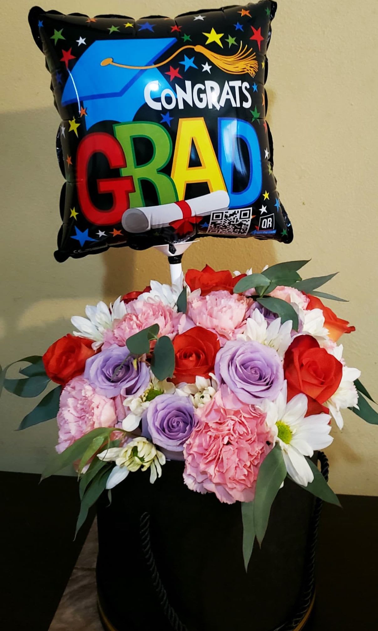 Colorful Graduation Box - Box of 10 Assorted Roses and Carnations with Daises and Accents of Eucalyptus. INCLUDES: A MINI GRAD BALLOON. Bouquet will be delivered approximately as pictured. ***  BALLOON DESIGN WILL VARY DEPENDING OF AVAILABILITY****