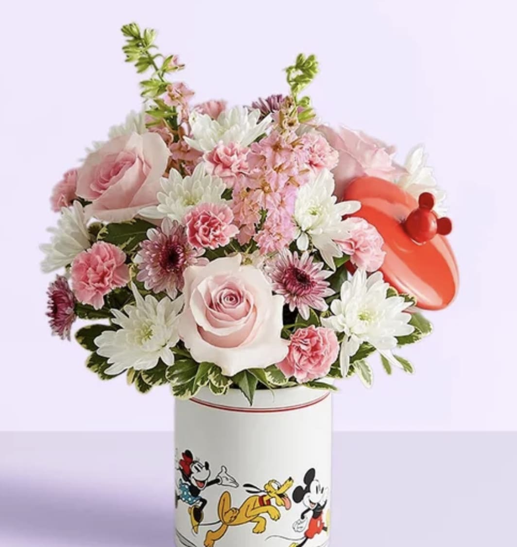 Disney Mickey Mouse &amp; Friends Cookie Jar-Baby Girl - Welcome the little princess with a gift full of character(s)! Part of our new Disney collection, this handcrafted bouquet is gathered in sweet pink and lavender blooms and designed in our whimsical Mickey Mouse and Friends cookie jar, featuring iconic animations. Great as a keepsake container or for keeping treats, it’s an adorable way to celebrate the littlest Disney fan and family.