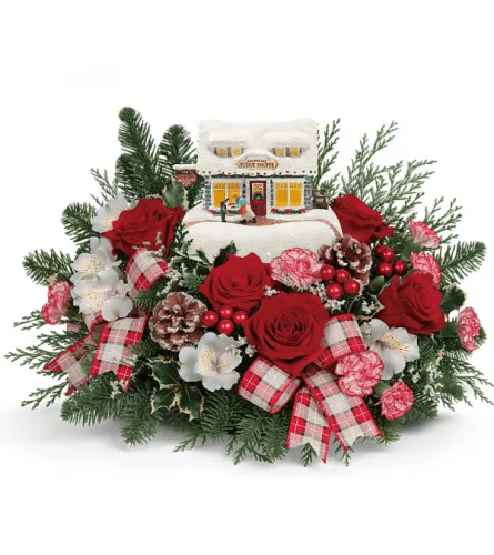 Thomas Kinkade “Fudge Shop Christmas” Centerpiece - Thomas Kinkade “Fudge Shop Christmas” Centerpiece – Floral Concepts Houston  Celebrate the season with the Thomas Kinkade Fudge Shop Christmas Centerpiece, a festive holiday floral arrangement designed exclusively at Floral Concepts Houston. This Christmas centerpiece combines the nostalgic charm of a hand-painted Thomas Kinkade collectible with fresh premium flowers and long-lasting winter evergreens.  A beautifully detailed Fudge Shop cottage sits at the heart of the design, surrounded by red roses, winter carnations, white alstroemeria, variegated holly, berries, pinecones, and classic plaid ribbon. The keepsake village building adds warmth and storybook magic, making this the perfect holiday table arrangement for families who love Christmas décor, village houses, and Thomas Kinkade art.  Crafted with premium blooms sourced from the best South American farms, this arrangement includes free same-day delivery in Houston and surrounding areas. Display the collectible cottage year after year to create a timeless holiday tradition.