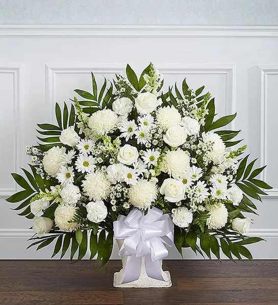 White floral standing arrangement with a white ribbon on a pedestal base