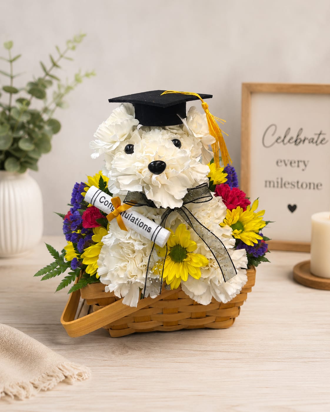 Graduation Puppy Flower Basket - Celebrate their big achievement with our Graduation Puppy Flower Basket, a fun and thoughtful graduation flower arrangement designed with a handmade white carnation puppy wearing a graduation cap. This keepsake-style basket is surrounded by bright seasonal flowers, making it perfect for high school, college, kindergarten, or any graduation celebration.  Each design is handcrafted by our local florists and delivered fresh. Flower colors may vary based on availability, but the graduation puppy style and celebratory look will remain the same. Available for same-day graduation flower delivery in Houston and surrounding areas.