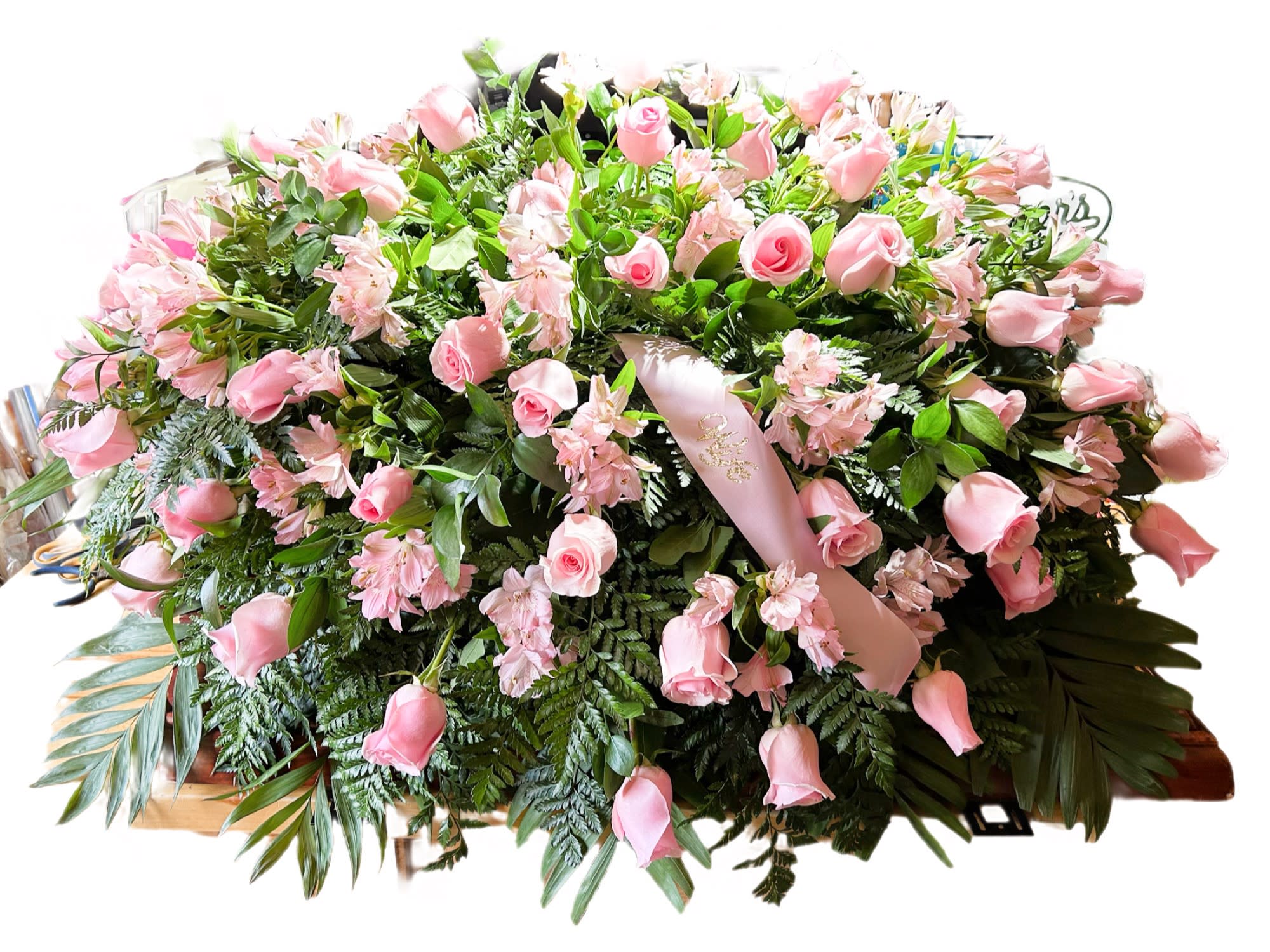 Pink Rose Casket Spray - The ultimate symbol of love and grace. This casket spray of pink roses is a beautiful way to honor someone who was and is deeply cherished. Adorned with 50 pink rose blooms and Pink Alstroemeria are accented with a pink satin ribbon an unforgettable way to commemorate a lifetime of unconditional love.  Ribbon can be changed to any wording or completely taken out of the casket spray. 
