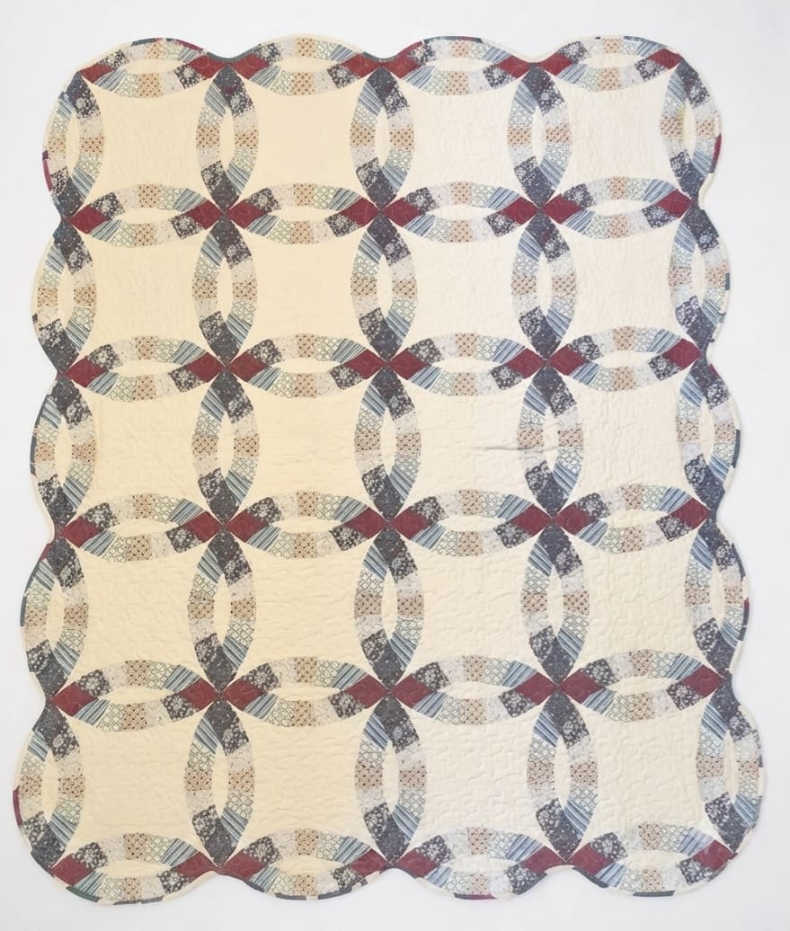 Cream quilt with a repeating oval chain pattern in muted red, blue, and gray