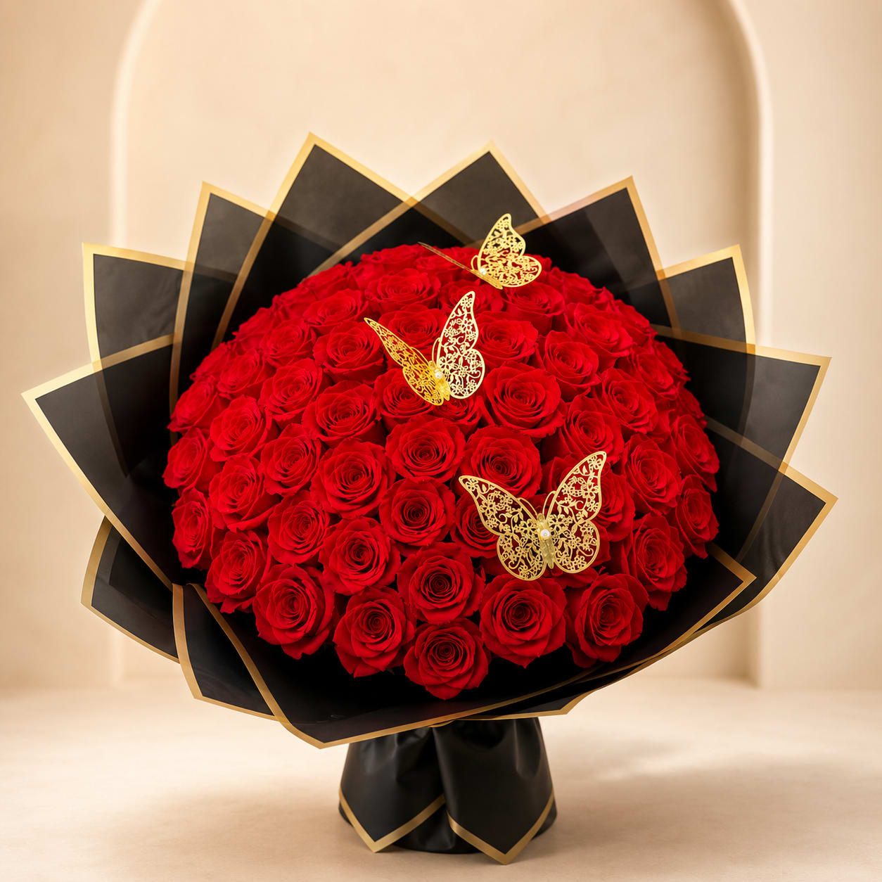 Large bouquet of red roses wrapped in black paper with gold trim and butterfly accents