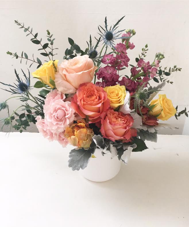 Mixed roses and thistle in a white vase