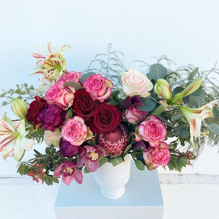 Love Potion - Love is in the air with lush orchids and bold king proteas. Designed to captivate, this vibrant centerpiece adds a modern romantic statement to any table with Cupid-inspired flair.