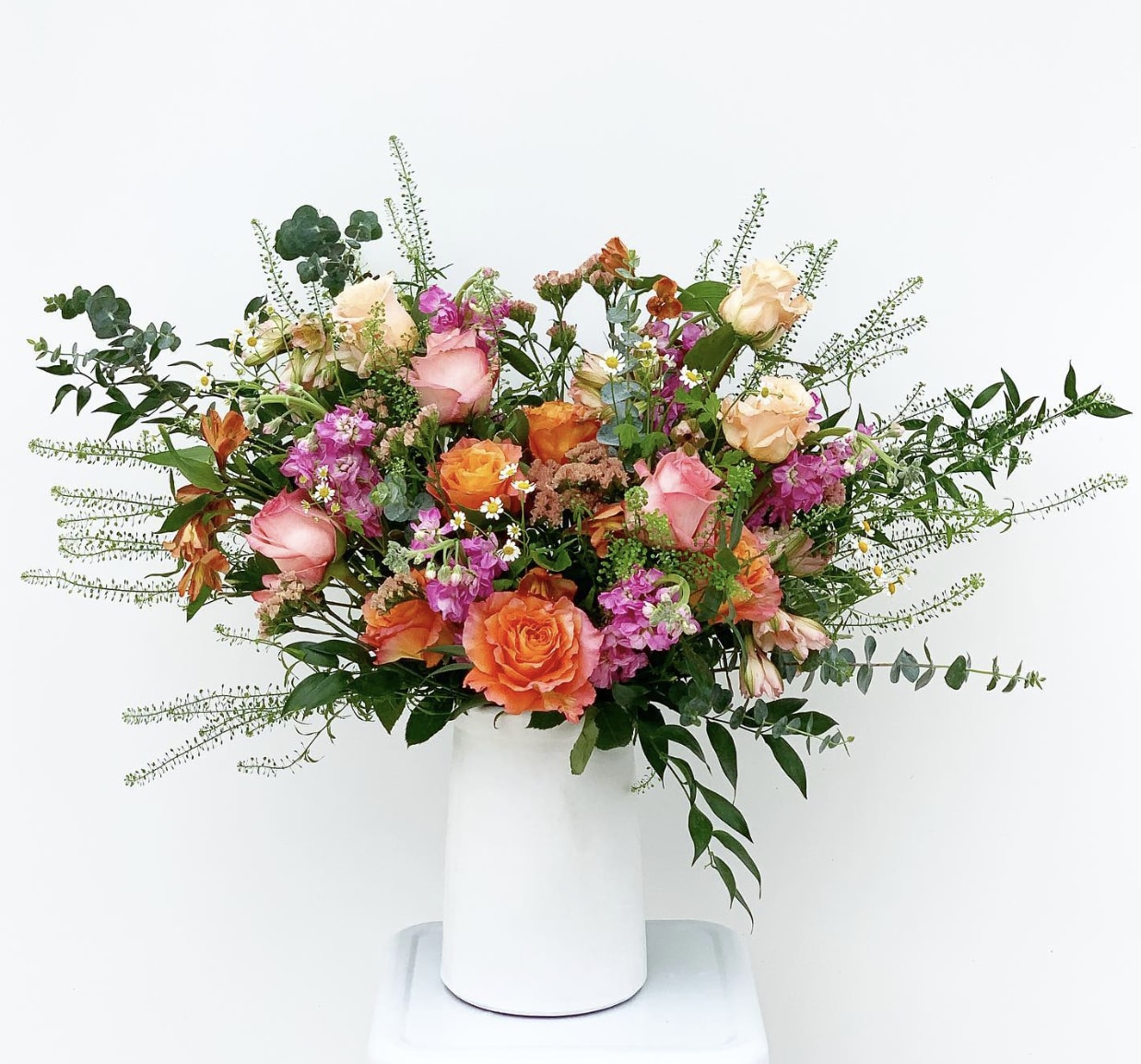 The Piper - Brighten any day with the Piper — a vibrant celebration of joy. Free Spirit roses and fuchsia stock make a bold, colorful statement, while blush roses add the perfect touch of softness. Pink and orange alstroemeria bring playful pops of color, complemented by cheerful feverfew and fresh eucalyptus. Designed to spark happiness for any occasion, the Piper radiates pure sunshine energy.