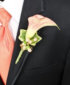 Calla lily boutonniere with pink ribbon on a black suit lapel