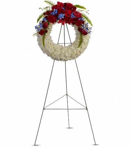 Standing floral wreath with red, white, and blue flowers on an easel
