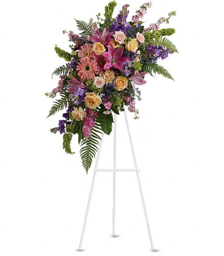 Standing floral spray with pink, purple, and peach blooms on a white easel