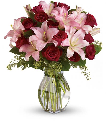 Bouquet of pink lilies and red roses in a clear glass vase