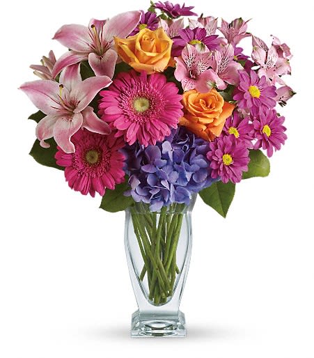 Mixed bouquet of lilies, roses, gerbera daisies, hydrangea, and daisies in a glass vase