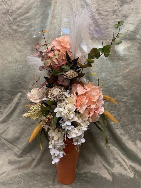 Tall floral arrangement in an orange vase with pink and white blooms