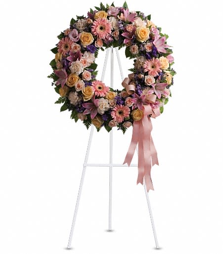 Floral wreath on a white stand with pink ribbon