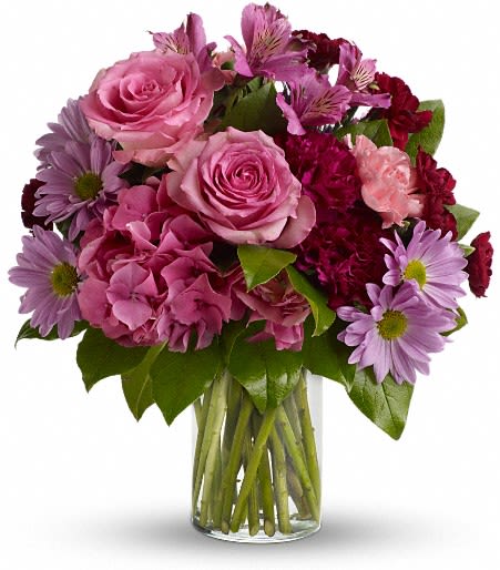 Pink roses and purple daisies in a clear glass vase