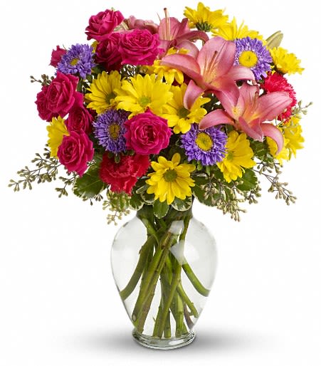 Bouquet of pink roses, lilies, and yellow daisies in a clear glass vase