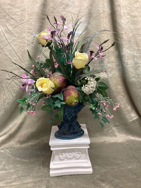 Tall floral arrangement with yellow roses and purple orchids in a dark vase