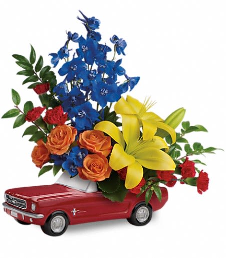 Flower arrangement in a red toy car with blue, orange, and yellow blooms