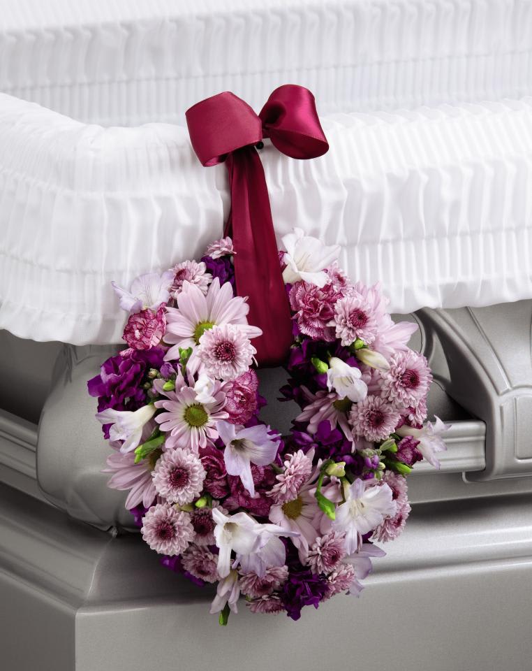 FTD Thoughts &amp; Prayers Wreath Adornment - The FTD Thoughts &amp; Prayers Wreath Adornment is a sweet accent  to symbolize your love and affection for the deceased. Lavender  carnations, freesia, daisies and button poms are accented with deep  magenta stock and arranged to form a 6-inch wreath which hangs from the  side of the casket from a burgundy wired ribbon.  10"h x 10"w