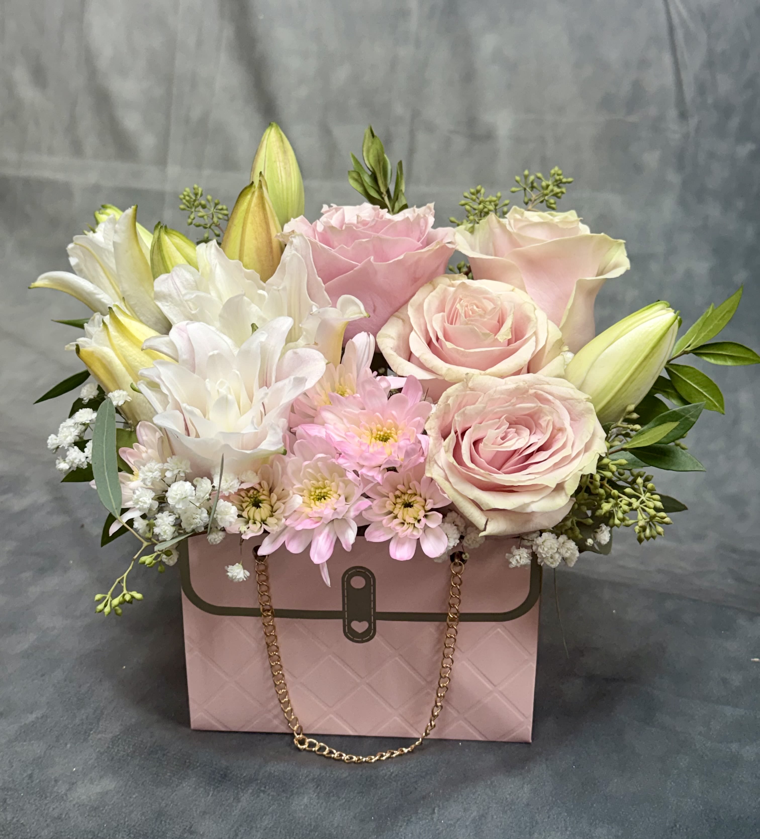 Pink and white flower arrangement in a pink handbag-style box
